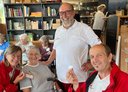 Drei Rotkreuz-Mitarbeiter:innen mit einer Teilnehmerin, im Hintergrund weitere Reiseteilnehmer:innen und Rotkreuz-Mitarbeiter:innen