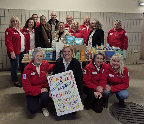 Gruppe von Mitarbeiterinnen und Mitarbeitern des Roten Kreuzes Himberg und der Faschingsgruppe „Himberger Farbenchaos“ bei der Übergabe von Sachspenden wie Hygieneartikeln und Babybedarf an die Rotkreuz-Tafel Himberg