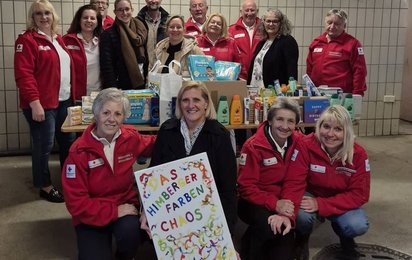 Gruppe von Mitarbeiterinnen und Mitarbeitern des Roten Kreuzes Himberg und der Faschingsgruppe „Himberger Farbenchaos“ bei der Übergabe von Sachspenden wie Hygieneartikeln und Babybedarf an die Rotkreuz-Tafel Himberg