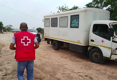 © Cruz Vermelha de Moçambique Rotkreuz Mitarbeiter mit roter Westen steht im Schlamm vor LKW in Mosambik nach Wirbelsturm Chido