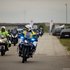 Ein Rotkreuz-Motorrad und ein Polizei-Motorrad fahren auf das Gelände zu - dahinter sieht man die anderen Motorräder.