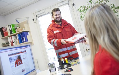 Ein junger Zivildiener in Uniform überreicht einer Rotkreuz-Mitarbeiterin ein Dokument