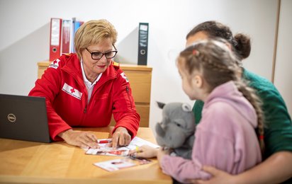 Rotkreuz-Mitarbeiterin betreut Kund:innen.