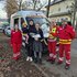 Baby Elias mit seinen Eltern und Rettungssanitäterinnen des Roten Kreuzes vor einem Rettungswagen im Freien.