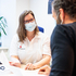 Am Bild berät eine Mitarbeiterin des Roten Kreuzes Tirol mit Maske einen Mann, der offensichtlich Migrationshintergrund hat in einem Büro