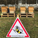 Im Vordergrund ein Schild mit den Worten "Vorsticht Bienen". Im Hintergrund Bienenstöcke im Seniorenwohnhaus Thalgau.