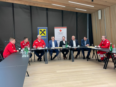 Vertreter von Rotem Kreuz und Raiffeisenbanken präsentieren die Unternehmenskooperation