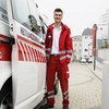Zivildiener unterstützen das Rote Kreuz: so auch Manuel, der gerade in Uniform bereit zum Dienst neben dem Rettungswagen steht.