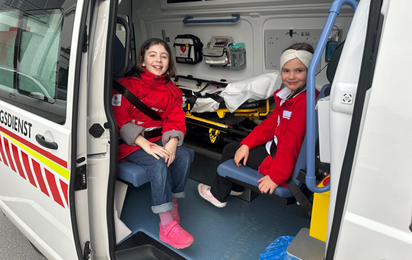 Jugendrotkreuzkinder sitzen in einem Krankentransportwagen bei geöffneter Türe.