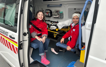 Jugendrotkreuzkinder sitzen in einem Krankentransportwagen bei geöffneter Türe.