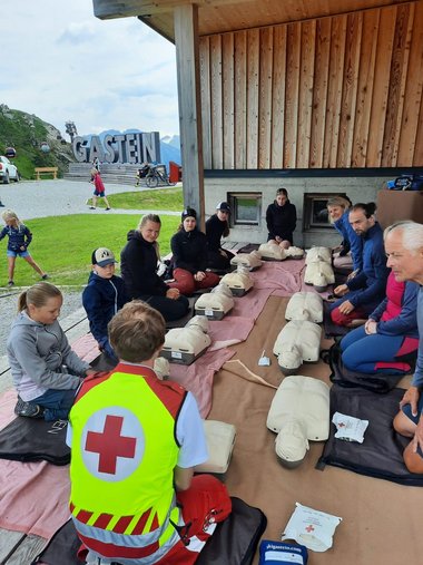 Erste-Hilfe-Lehrbeauftrager mit Schulungs-Teilnehmerinnen und vor diesen liegenden Übungspuppen.