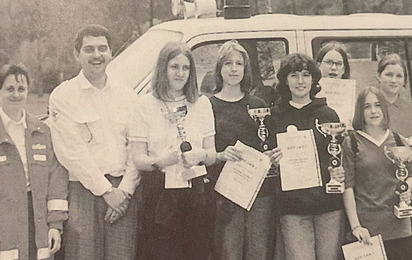 Stolze Kinder mit ihren Betreuern präsentieren ihre Auszeichnungen bei Jugendbewerben.