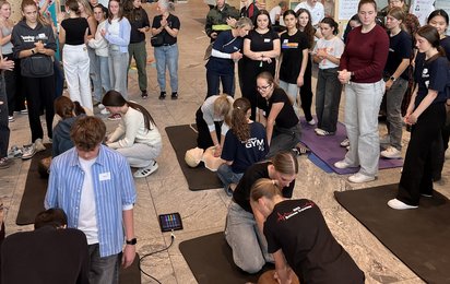 Schüler:innen trainieren die Wiederbelebung an Übungspuppen.