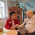 Ein junger Rotkreuz-Mitarbeiter beim Besuchsdienst. Er besucht einen älteren Mann und verbringt mit ihm Zeit.