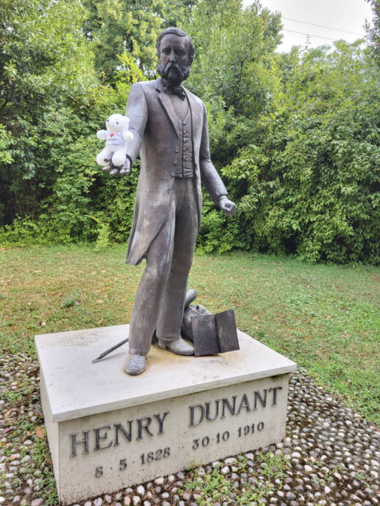 Bärli sitzt in der Hand einer Bronzestatue von Henry Dunant in Solferino.