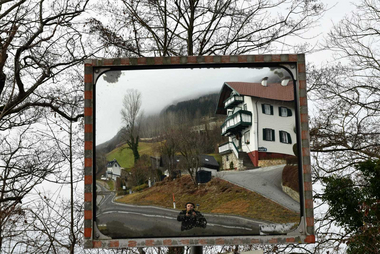Spiegelung eines Hauses und einer Straße in einem Verkehrsspiegel