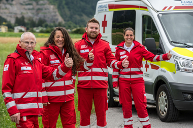 Vier Sanitäterinnen stehen mit Uniform vor einem REttungsauto und halten ihrn Daumen in die Höhe