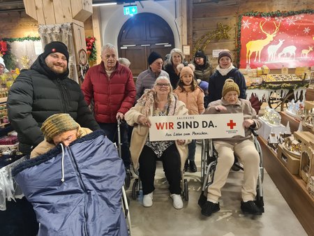 Eine Gruppe mit Pflegekräften und Bewohner:innen des Seniorenwohnhauses Hallein am Christkindlmarkt.