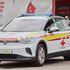 Ein Mitarbeiter vom Roten Kreuz steht an der Seite vom ersten voll elektrischen Fahrzeug für den hausärztlichen Notdienst.