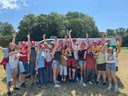 eine Gruppe von Kindern, Jugendlichen und Jugend-Betreuer:innen steht vor einem Bus und lächeln in die Kamera zum Abshcluss des Lagers