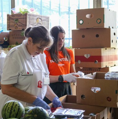 © Rotes Kreuz Graz-Stadt / L. Vorraber Zwei Frauen, eine von der Team Österreich Tafel und eine von Amazon, sortieren zusammen Lebensmittelspenden.