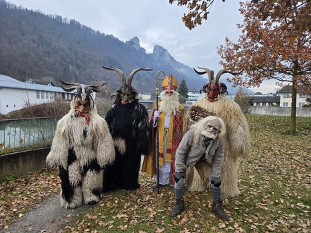 Nikolaus und vier Krampusse gemeinsam im Freien. Im Hintergrund sind die Barmsteine zu sehen.
