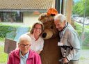Reiseteilnehmer:innen mit einem Bären-Maskottchen