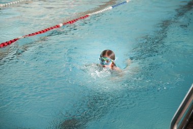 Ein Mädchen mit Schwimmbrille schwimmt in einem Becken