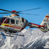 Der in St. Johann stationierte Rotkreuz-Hubschrauber fliegend vor einer winterlichen Gebirgslandschaft