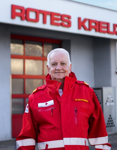 Harald Glantschnigg steht vor den Rolltoren an der Dienststelle in Traun in seiner roten Uniform.