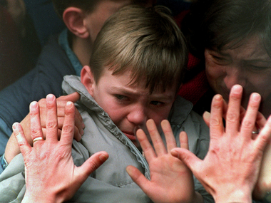 © Laurent Rebours A father's hands press against the window of a bus carrying his tearful son and wife to safety from the besieged city of Sarajevo during the Bosnian War on Nov. 10, 1992.