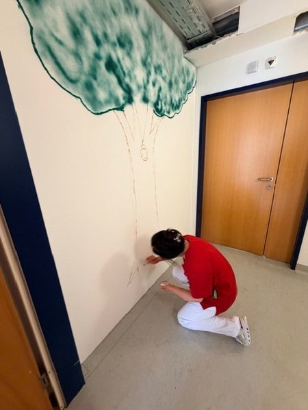 Eine Rotkreuz-Mitarbeiterin bemalt eine Wand.
