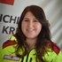 Frau Michaela Scheiber in Rotkreuz-Uniform vor einer Rotkreuz-Standarte.