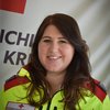 Frau Michaela Scheiber in Rotkreuz-Uniform vor einer Rotkreuz-Standarte.