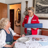 Eine Zuhause-Essen-Mitarbeiterin liefert eine Essenspaket an eine Klientin