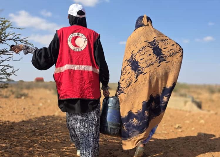 Rotkreuzmitarbeiterin hilft Person in Somalia dabei, Wasser zu tragen