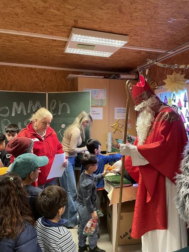 Der Nikolaus verteilt mit Unterstützung zweier Mitarbeiter:innen Geschenke an die Kinder.