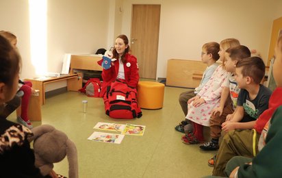 © Credit: OÖRK / Ried Die Rotkreuz-Mitarbeiterin Lina ist mit ROKO zu Besuch im Kindergarten und zeigt den Kindern dort spielerisch wie man ERste-Hilfe leistet.