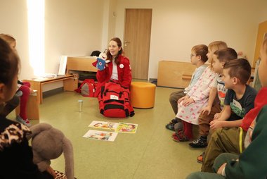 Die Rotkreuz-Mitarbeiterin Lina ist mit ROKO zu Besuch im Kindergarten und zeigt den Kindern dort spielerisch wie man ERste-Hilfe leistet.