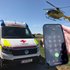 Einblendung eines Handys, bei dem gerade der Notruf 144 gewählt wird, im Hintergrund ist ein Rettungsauto vom Roten Kreuz und ein ÖAMTC Rettungshubschrauber