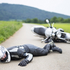 Unfall mit einem Motorrad. Ein Motorradfahrer mit Helm liegt auf dem Boden.