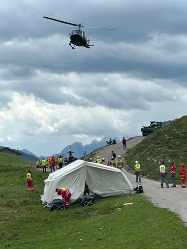 Ein Hubschrauber befindet sich in der Luft über einem weißen Zelt und Einsatzkräften.