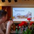 Bildschirm mit der Präsentation bei der Generalversammlung 2024. Die Gäste sitzen im Vordergrund