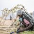 Eine sudanesische Frau sitzt in einem Flüchtlingscamp im Tschad auf dem Boden und bearbeitet mit ihren Händen Pflanzen.