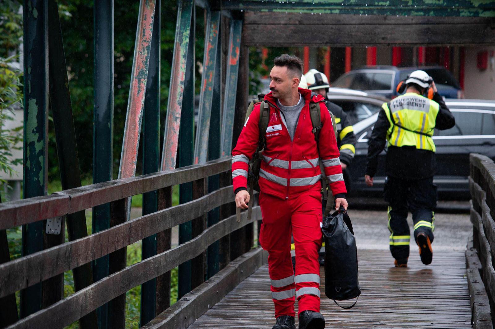 Hochwasser 2023 in Kärnten - © ÖRK / LV Kärnten Rotkreuz-Mitarbeiter in Uniform geht über eine Brücke.