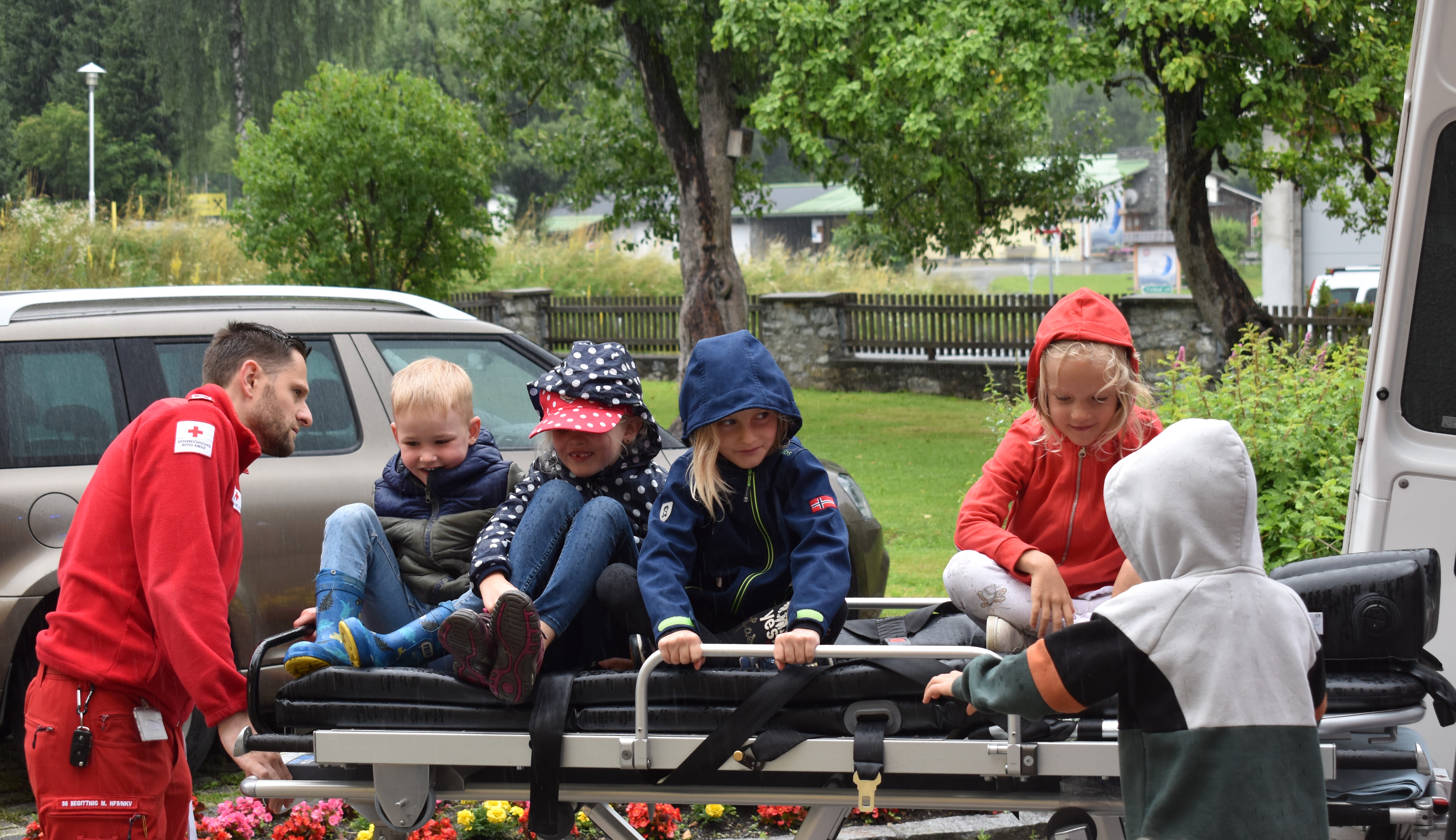 Besuch des Rettungswagens im Kindergarten. Lachende Kinder auf der Rettungstrage.