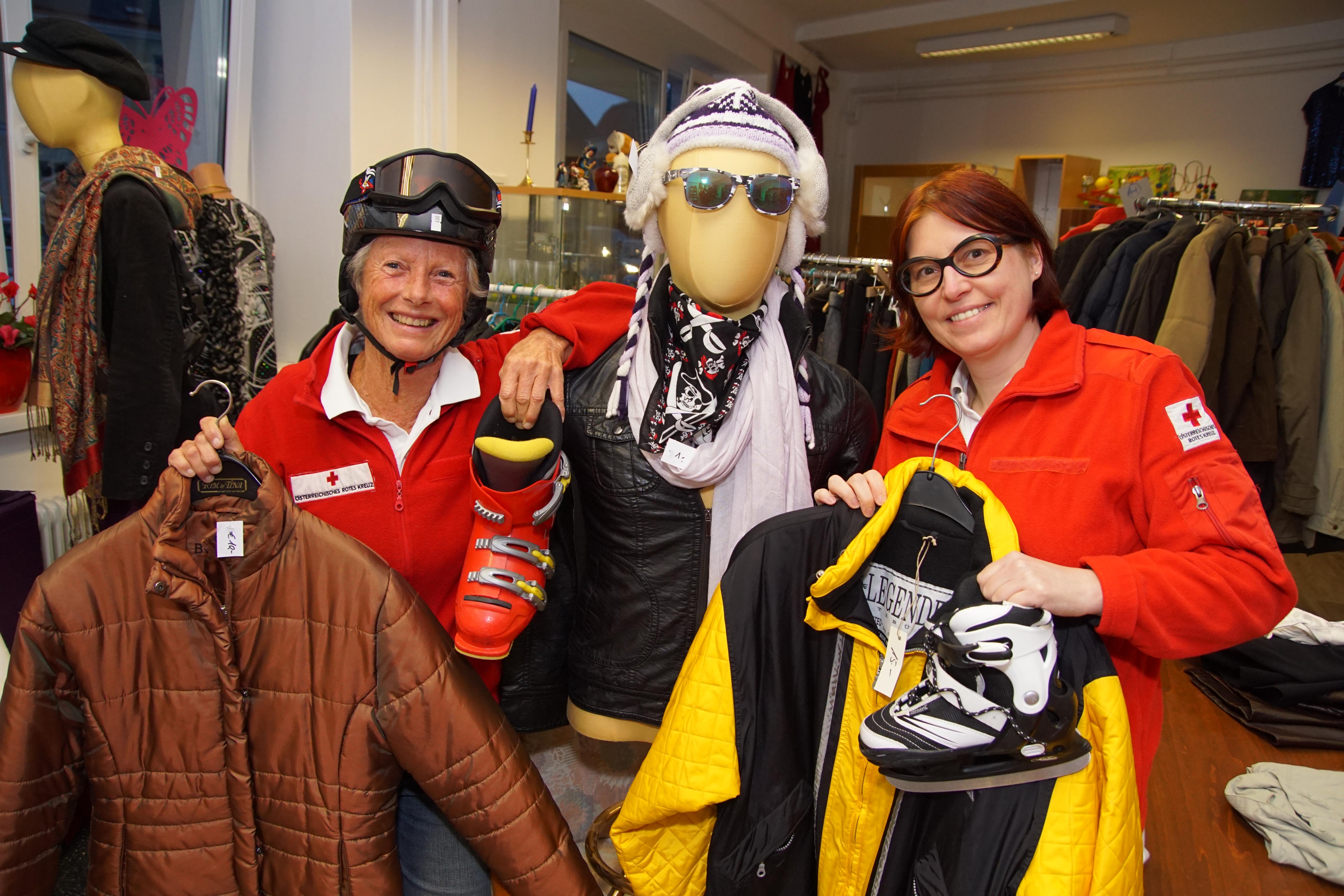 Zwei Mitarbeiterinnen zeigen Winterjacken und Skischuhe.