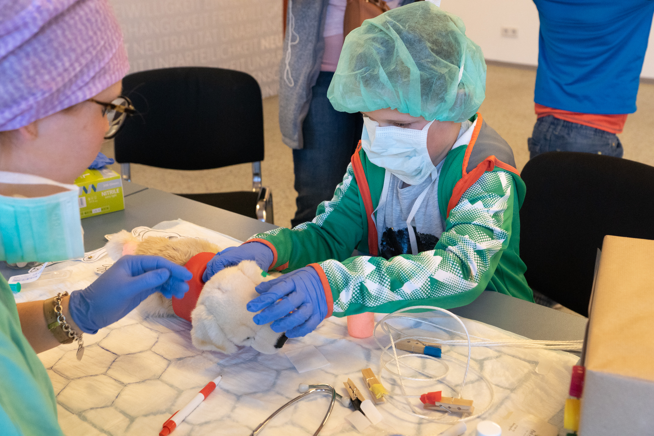 Teddyklinik - © RKJ Brunn Ein Kind in OP-Kleidung untersucht sein Stofftier im Rahmen der Teddyklinik