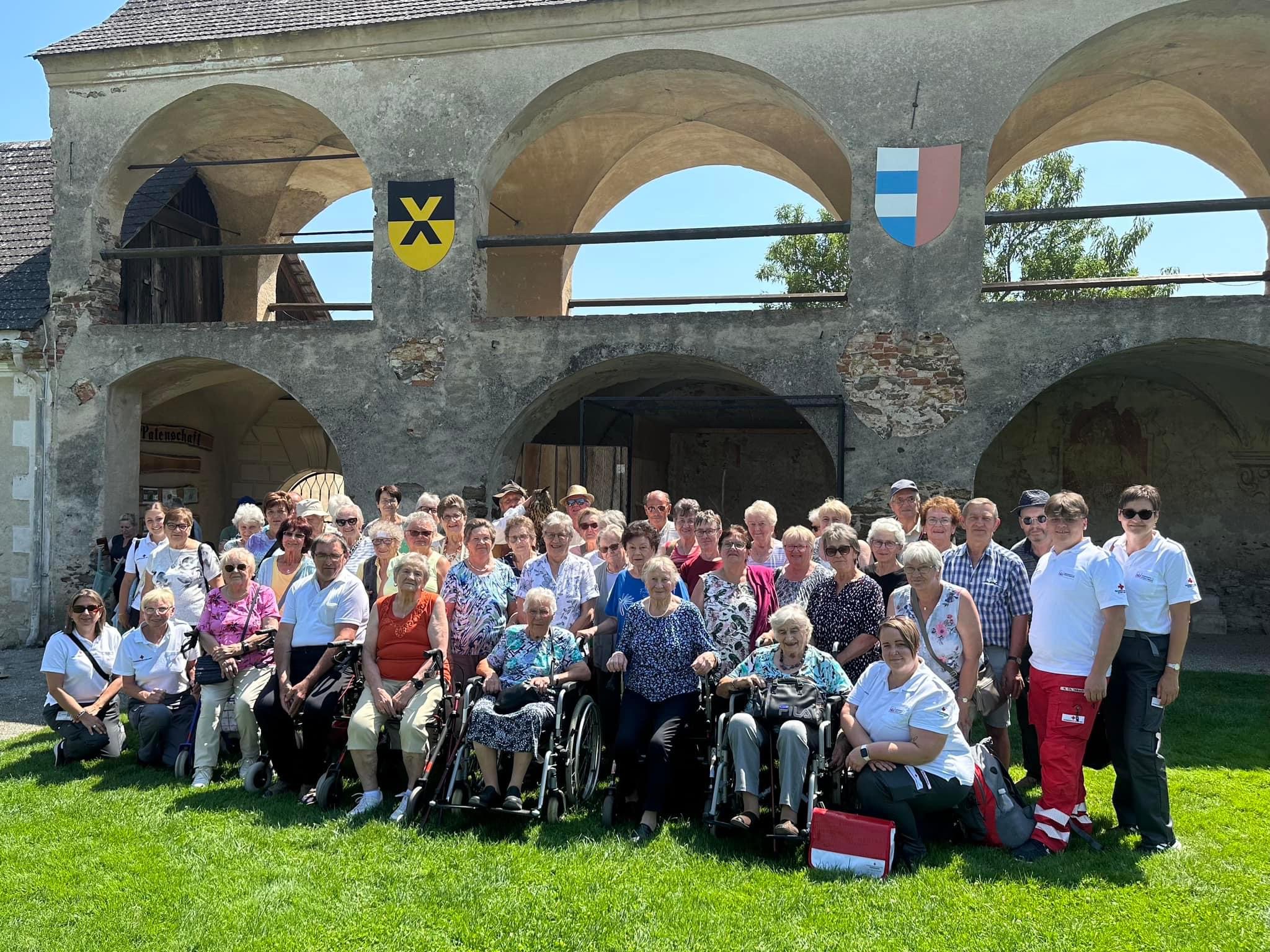 Eine Gruppe des Betreuten Reisen vom Roten Kreuz Waidhofen/Thaya anlässlich einer Reise auf einer Wiese vor einem historischen Gebäude.