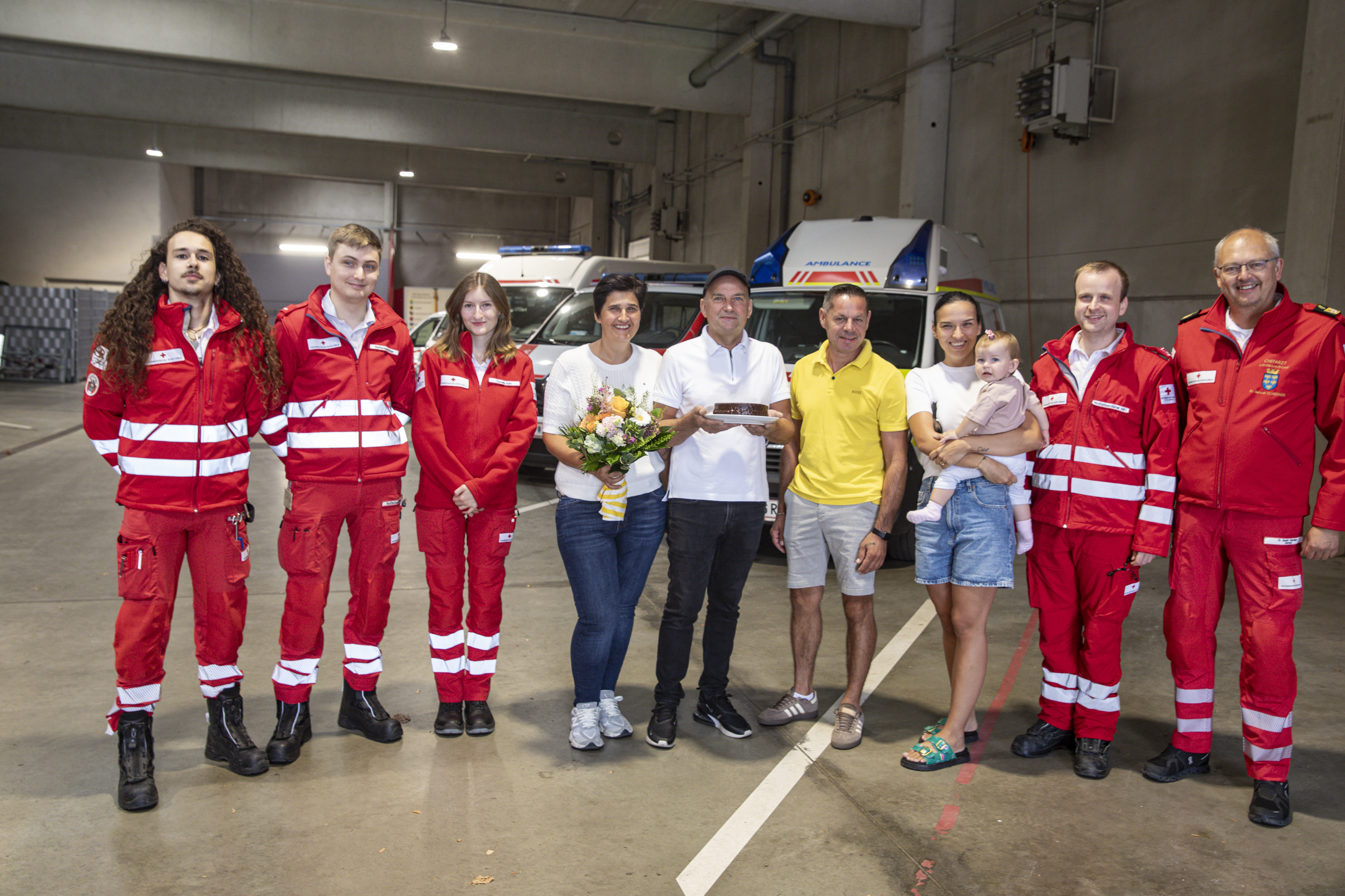 Gruppenfoto aller Sanitäter:innen und Patient:innen in der Rotkreuz-Garage.